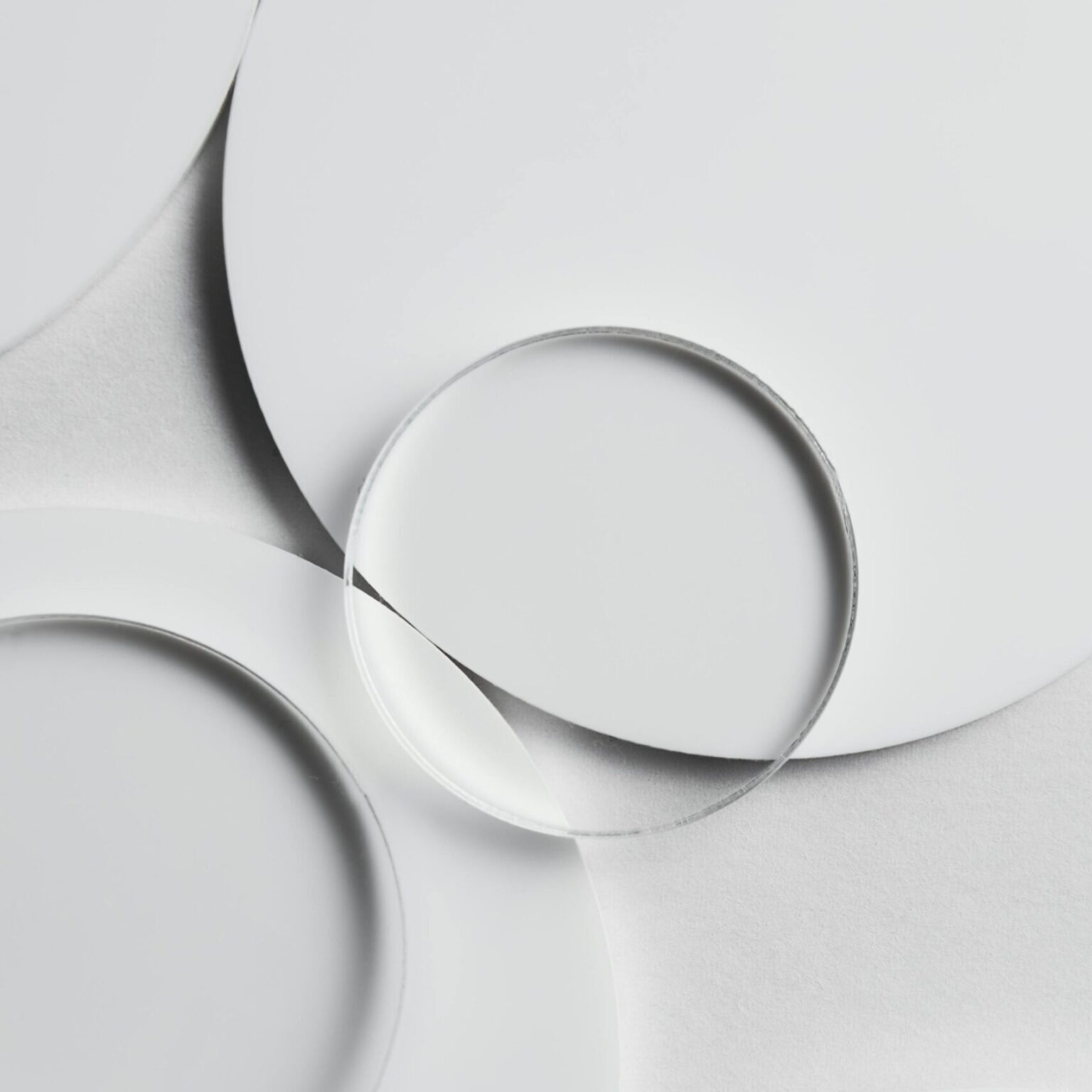 Artistic top view of overlapping glass and ceramic plates on a white surface.